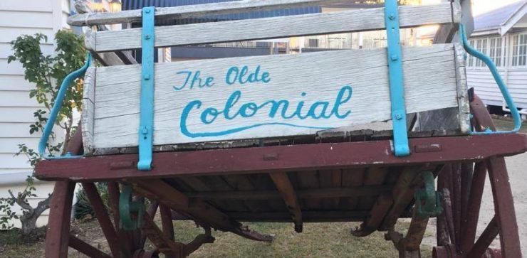 wooden dray with sign for Colonial Motor Inn Monto